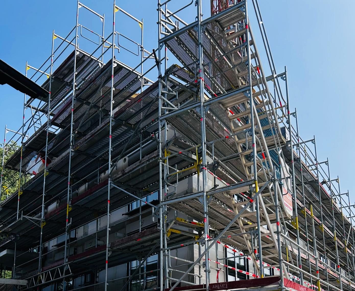 Mehrfamilienhaus im Rohbau, vollständig eingerüstet, vor dem Aufbringen der Klinkerfassade