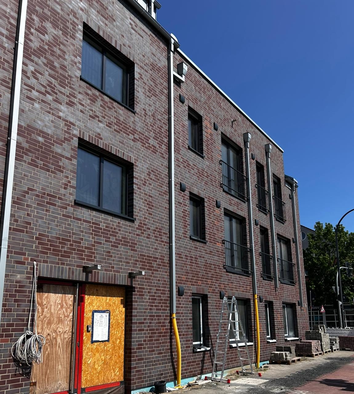 Fertige rotbraune Klinkerfassade des Mehrfamilienhauses von der Straße aus gesehen