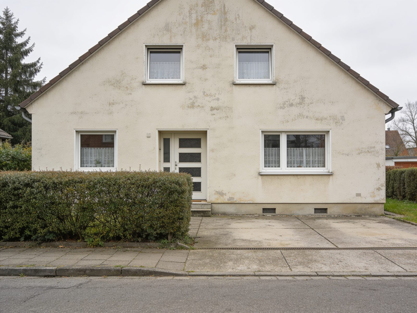 Wohnhaus mit verwitterter Putzfassade vor der Sanierung